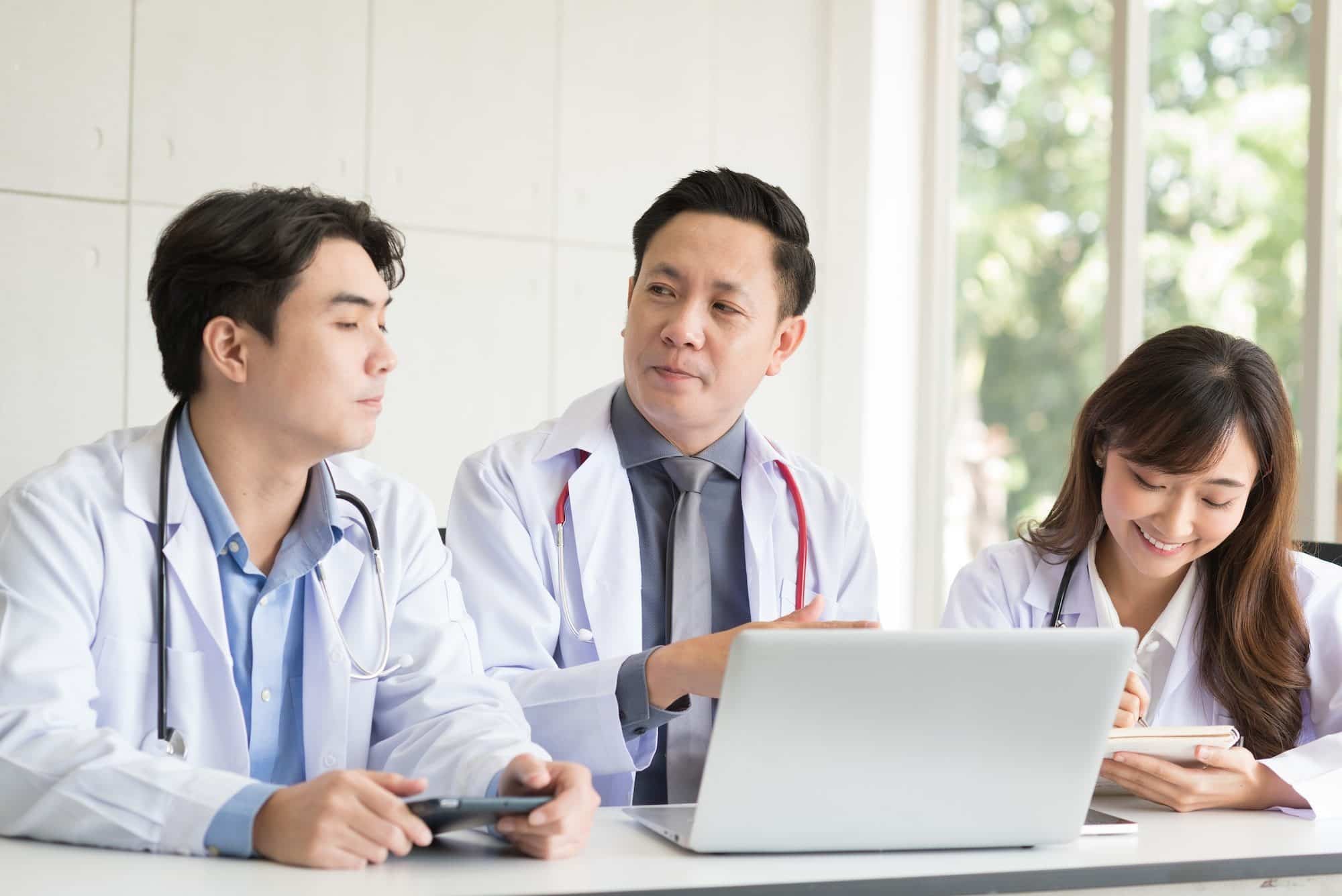 Group of Asian doctor meeting and discuss with other colleagues in modern office clinic room.