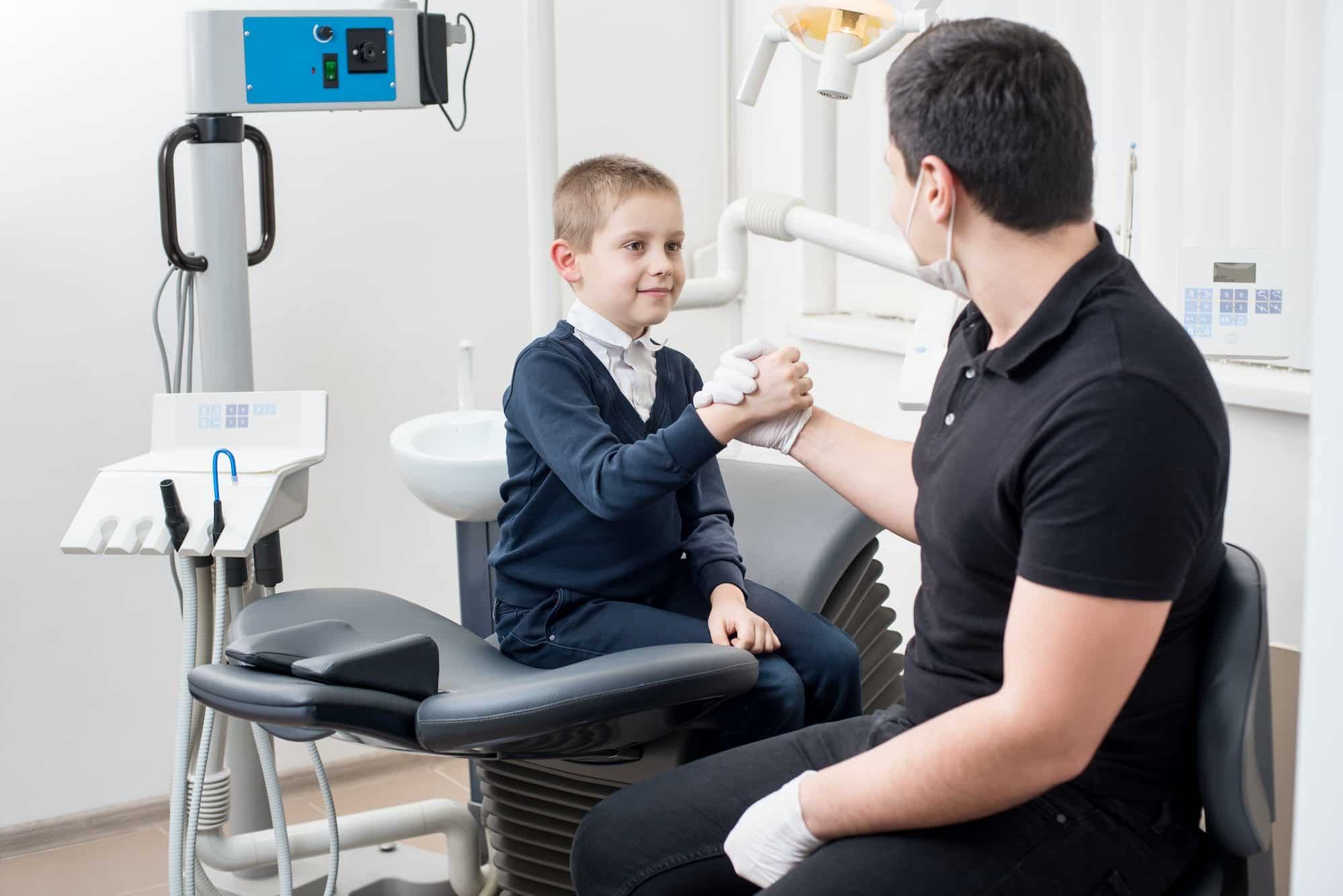 Pediatric dentist shake hands with young boy.