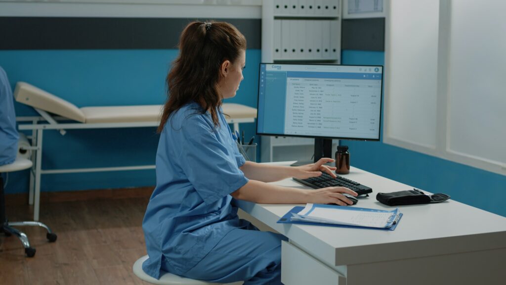 Woman working as nurse with computer and documents