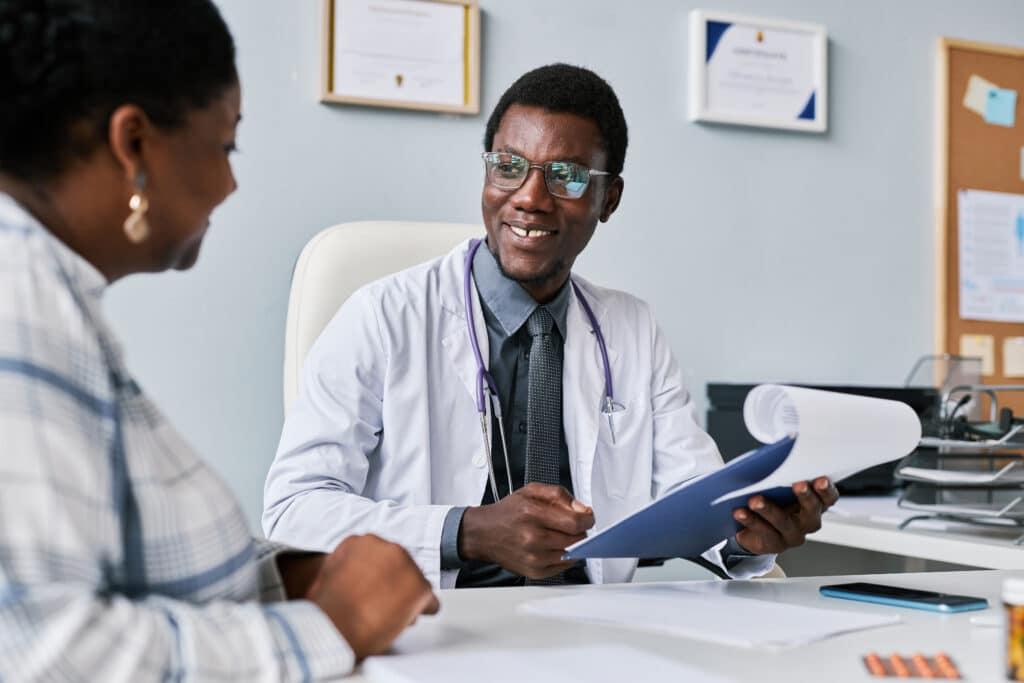 Smiling black doctor consulting female doctor in clinic