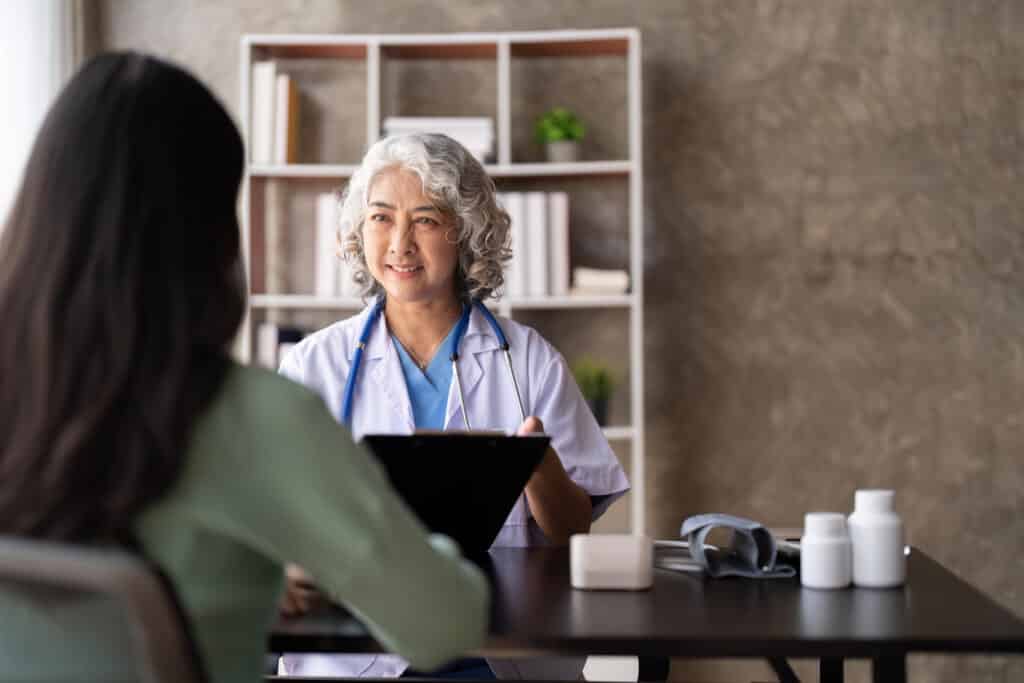 Woman senior doctor is Reading Medical History of Female Patient and Speaking with Her During